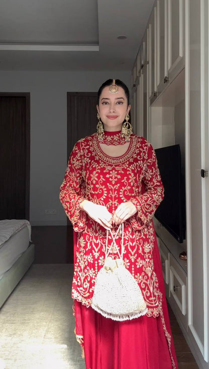 Full-length view of a red georgette sharara suit on a mannequin showing the intricate gold vine embroidery on the kurta and bottom hem.